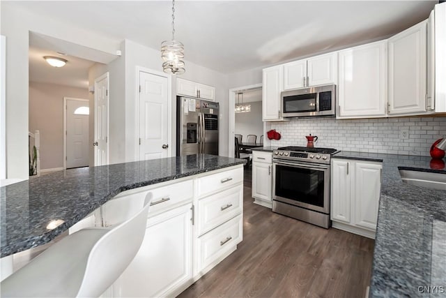 kitchen with white cabinetry, appliances with stainless steel finishes, decorative light fixtures, and tasteful backsplash