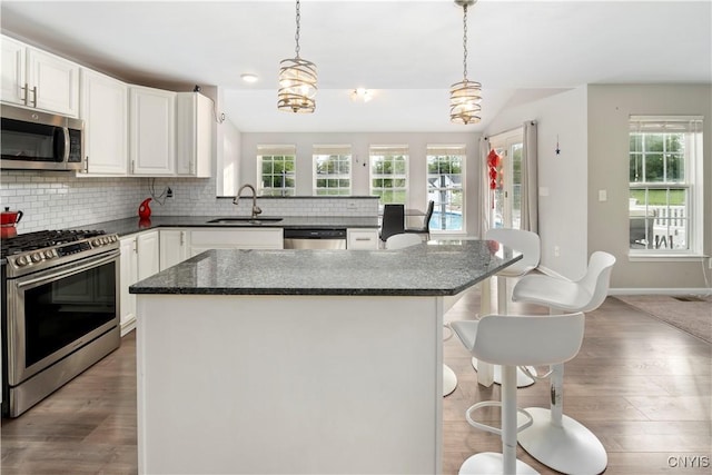 kitchen with sink, white cabinetry, a center island, hanging light fixtures, and appliances with stainless steel finishes