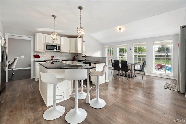 kitchen featuring sink, dark wood-type flooring, appliances with stainless steel finishes, tasteful backsplash, and decorative light fixtures