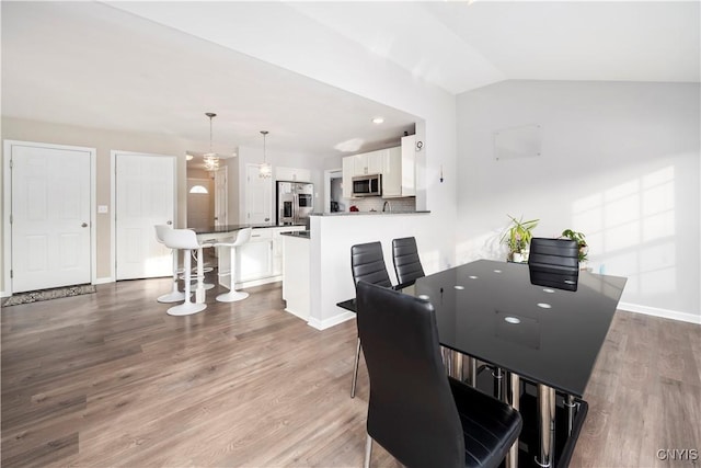 dining space with vaulted ceiling and wood-type flooring