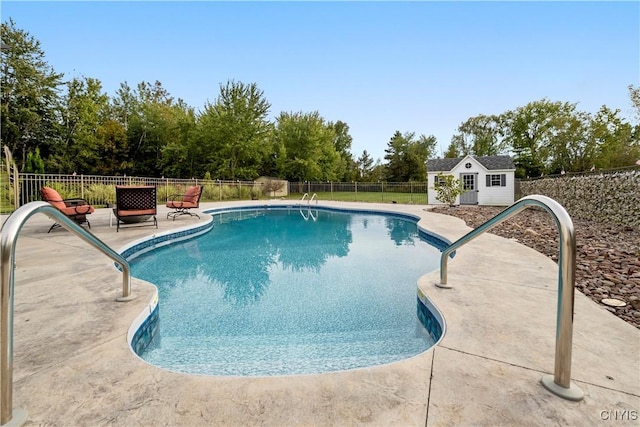 view of pool with a patio, an outbuilding, and a fire pit