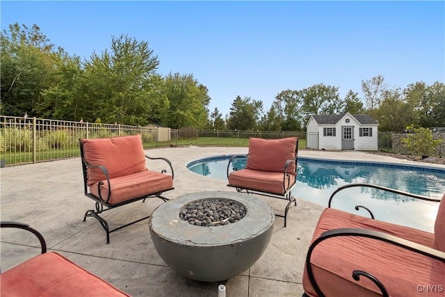 view of swimming pool with an outdoor structure, a patio area, and a fire pit