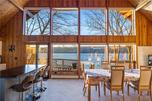 dining room with a water view, wooden ceiling, baseboard heating, and a high ceiling