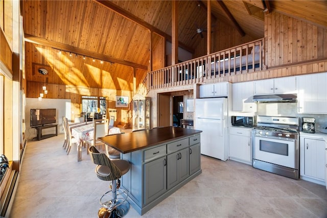 kitchen with high vaulted ceiling, stainless steel range with gas stovetop, white cabinets, and white refrigerator