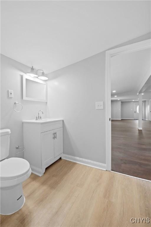 bathroom featuring wood-type flooring, toilet, and vanity