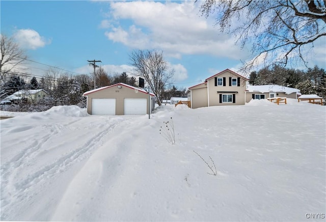 snowy yard featuring a garage and an outdoor structure