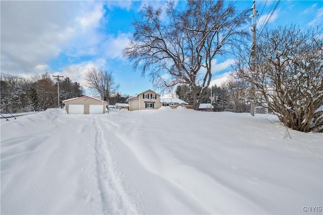 yard layered in snow with an outbuilding and a garage