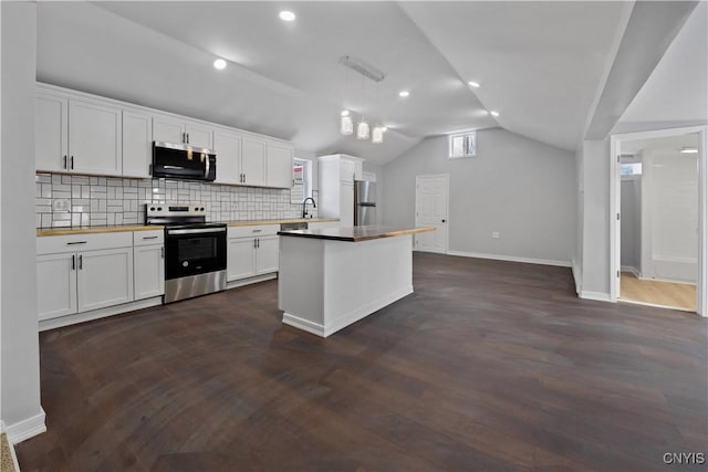 kitchen with lofted ceiling, hanging light fixtures, stainless steel appliances, and white cabinets