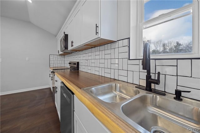 kitchen with lofted ceiling, sink, wooden counters, appliances with stainless steel finishes, and white cabinets