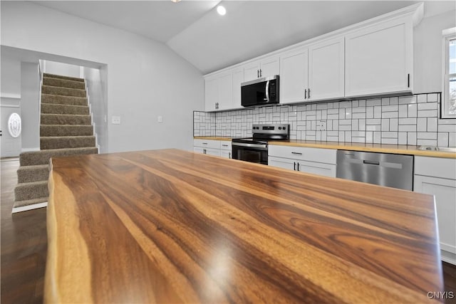 kitchen featuring vaulted ceiling, wood counters, white cabinetry, backsplash, and stainless steel appliances