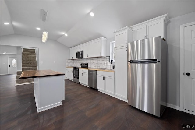 kitchen with white cabinets, vaulted ceiling, appliances with stainless steel finishes, and wooden counters