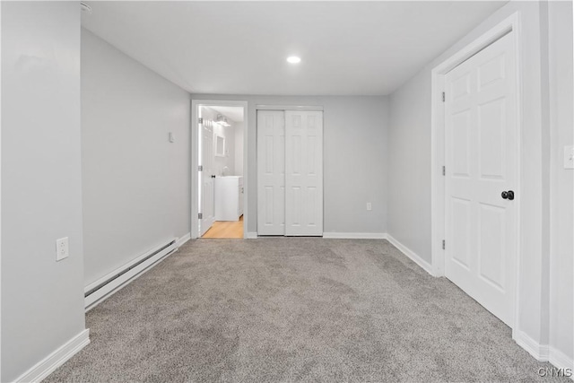 unfurnished bedroom with light carpet, a baseboard heating unit, and ensuite bathroom