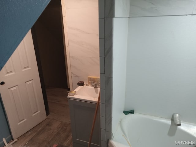 bathroom featuring hardwood / wood-style flooring, a bathing tub, tile walls, and vanity