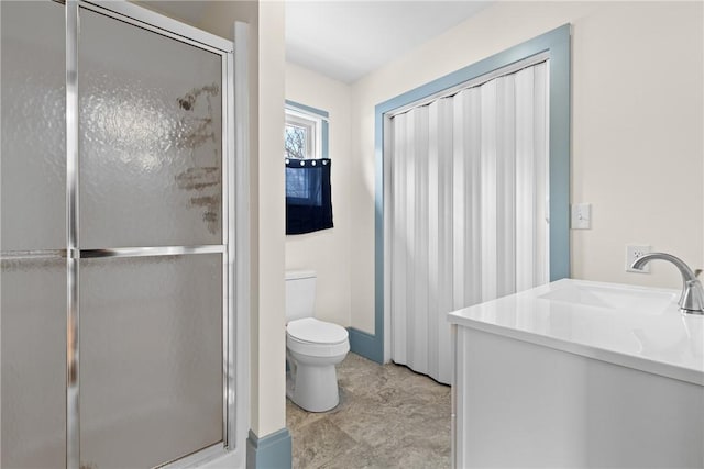 bathroom featuring toilet, vanity, and a shower with shower door