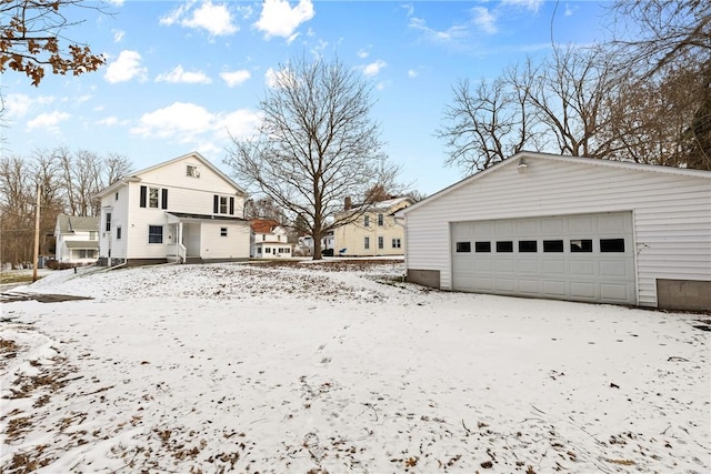 snow covered property with a garage and an outdoor structure