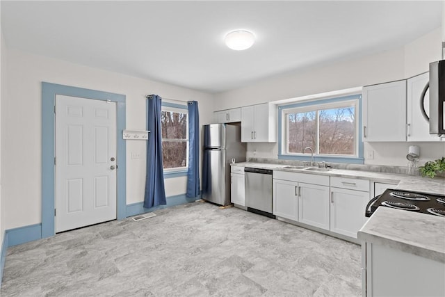 kitchen with stainless steel appliances, a wealth of natural light, sink, and white cabinets