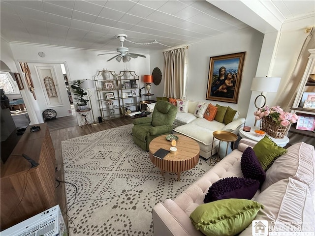 living room with wood-type flooring, ornamental molding, and ceiling fan