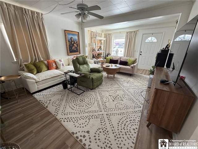 living room featuring wood-type flooring, crown molding, and ceiling fan