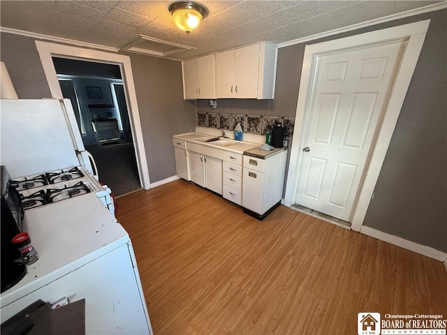 kitchen with white cabinetry, white appliances, sink, and light hardwood / wood-style flooring