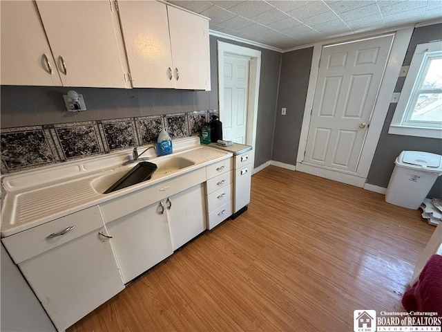 kitchen featuring white cabinetry, sink, light wood-type flooring, and decorative backsplash