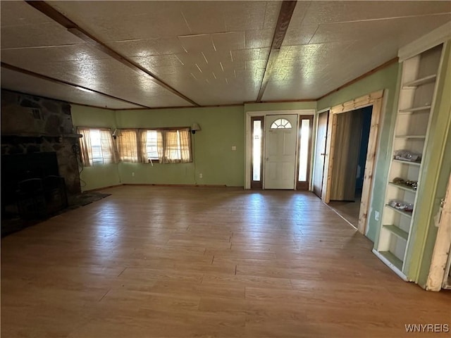 foyer with wood-type flooring and a stone fireplace