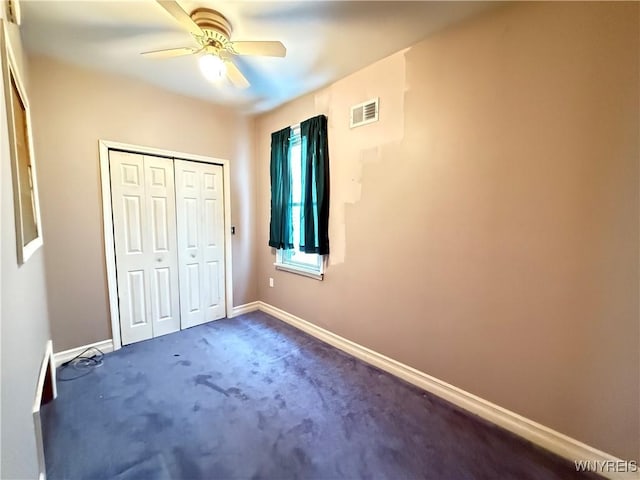 unfurnished bedroom with ceiling fan, dark carpet, and a closet