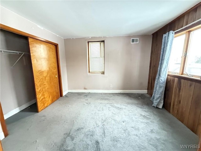 unfurnished bedroom featuring wooden walls and a closet