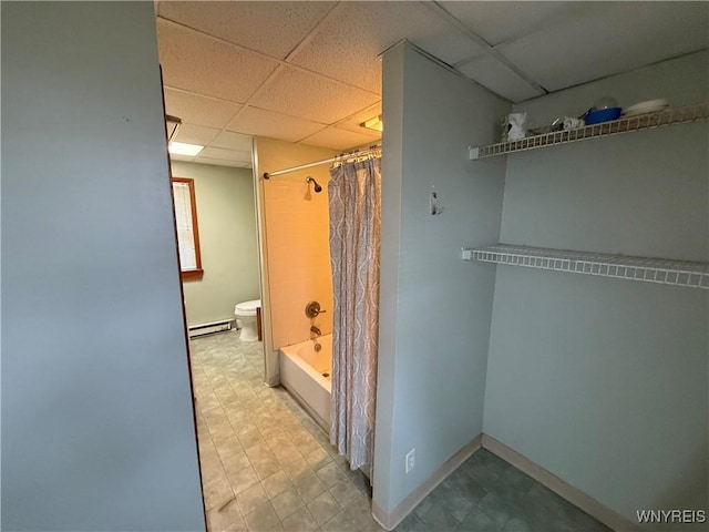 bathroom with a paneled ceiling, shower / bath combination with curtain, baseboard heating, and toilet