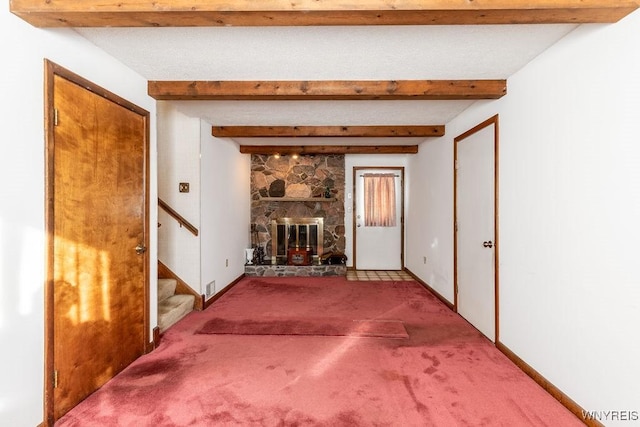 unfurnished living room featuring beam ceiling, a fireplace, and light colored carpet