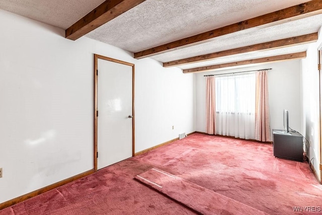 carpeted empty room featuring beam ceiling and a textured ceiling