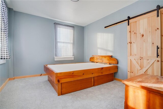 carpeted bedroom with baseboards and a barn door