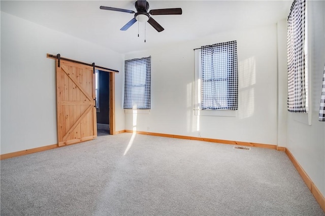 unfurnished bedroom with baseboards, a barn door, and carpet