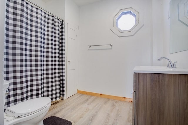 bathroom featuring baseboards, toilet, vanity, and wood finished floors
