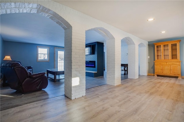 living room with a brick fireplace and light wood-type flooring