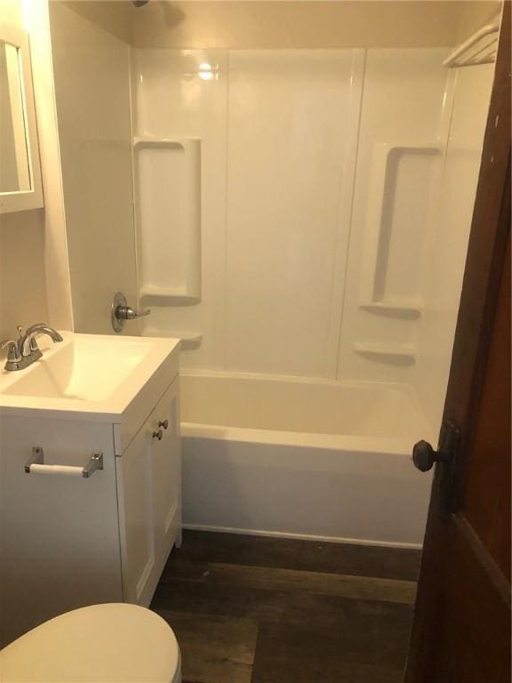 full bathroom featuring hardwood / wood-style flooring, vanity, tub / shower combination, and toilet