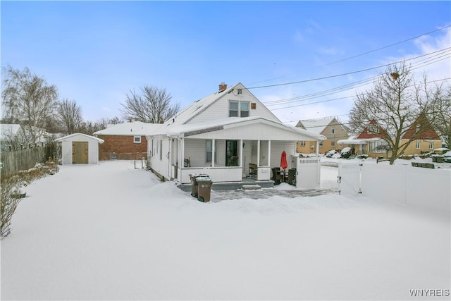 snow covered property with a storage unit and a porch