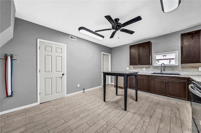 kitchen featuring decorative backsplash, range, sink, and light hardwood / wood-style flooring