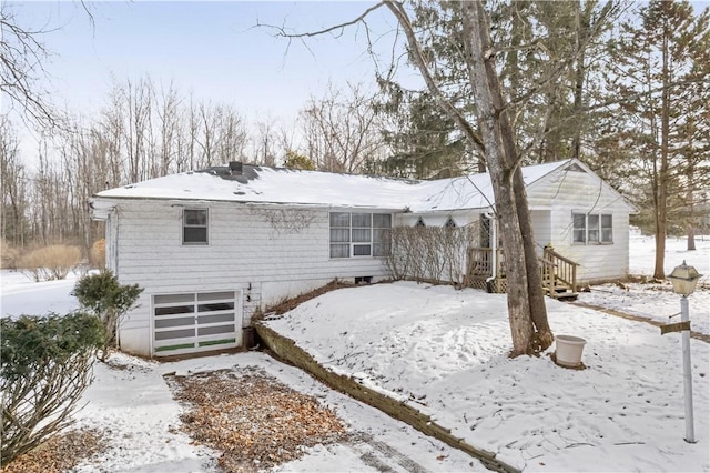 snow covered rear of property with a garage