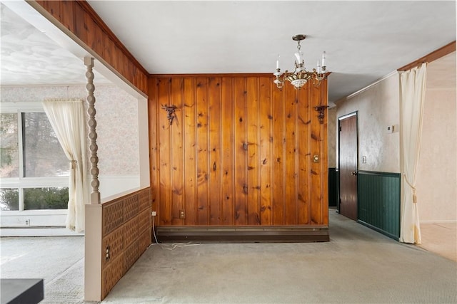 empty room with a healthy amount of sunlight, a baseboard heating unit, light colored carpet, and wooden walls