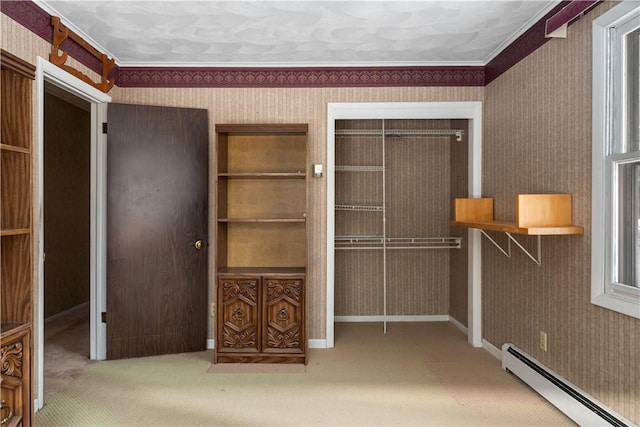 unfurnished bedroom featuring ornamental molding, carpet flooring, a closet, and a baseboard heating unit