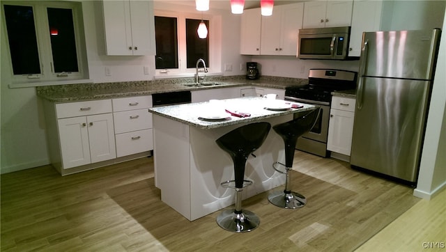 kitchen with stainless steel appliances, a center island, sink, and white cabinets