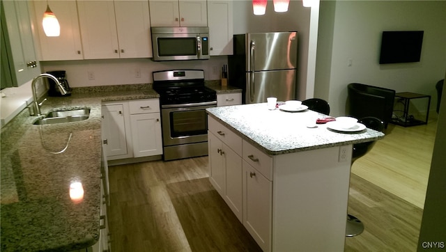 kitchen featuring sink, white cabinetry, hanging light fixtures, appliances with stainless steel finishes, and a kitchen island