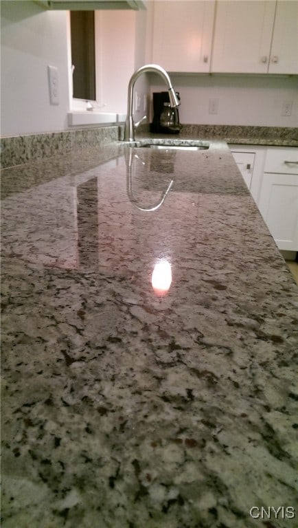 kitchen featuring stone counters, sink, and white cabinets