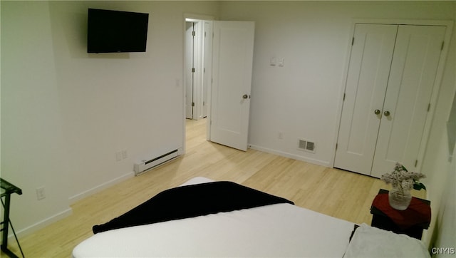 bedroom featuring a baseboard radiator, a closet, and light wood-type flooring