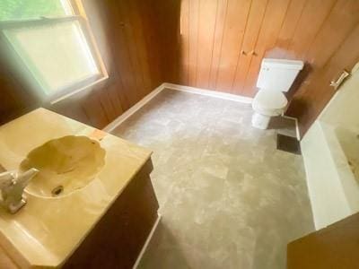 bathroom with vanity, wooden walls, and toilet