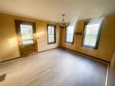 unfurnished dining area featuring hardwood / wood-style flooring and an inviting chandelier