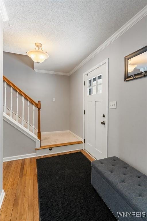 entryway featuring hardwood / wood-style flooring, ornamental molding, and a textured ceiling