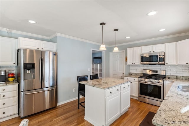 kitchen featuring a kitchen island, pendant lighting, white cabinetry, a kitchen breakfast bar, and stainless steel appliances