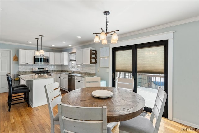 dining room with crown molding, a healthy amount of sunlight, a chandelier, and light hardwood / wood-style floors