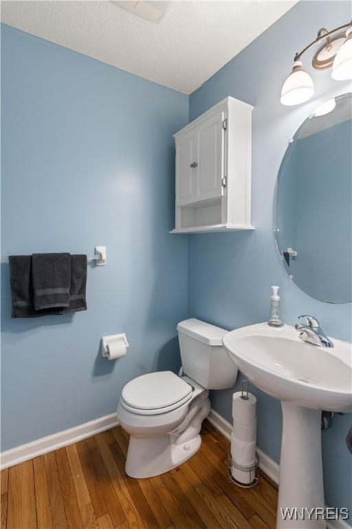 bathroom featuring toilet, hardwood / wood-style floors, and a textured ceiling